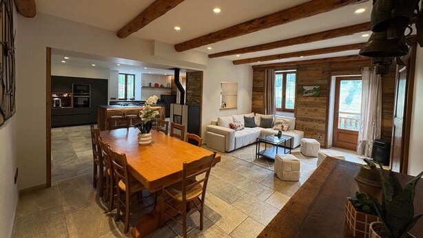 A spacious living area with a wooden dining table, a sofa set, and a kitchen in the background. - Splendid alpine apartment - 10 guests (Les Saisies)