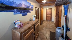 A wooden interior with a bench, a vase with flowers, and a wall with a mountain landscape. - Splendid alpine apartment - 10 guests (Les Saisies)