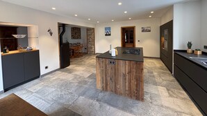 A modern kitchen with a central island, dark cabinetry, and a dining area in the background. - Splendid alpine apartment - 10 guests (Les Saisies)