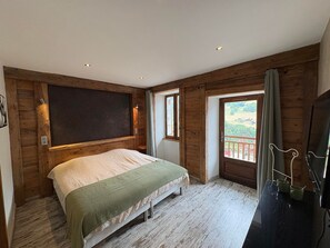 Ein Schlafzimmer mit Bett, Holzwänden, einem Balkon mit Blick und einem Fernsehgerät auf einem Schrank.