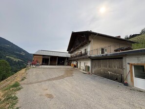 Ein zweistöckiges Gebäude mit Garage, überdachter Terrasse und Blick auf eine hügelige Landschaft.
