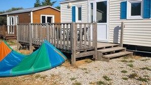 Uma casa móvel com um deck de madeira e uma tenda colorida em primeiro plano.