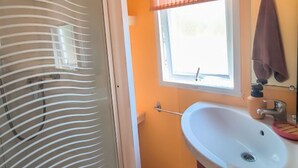 Um banheiro com pia branca, uma janela com persianas e uma toalha pendurada em um porta-toalhas.