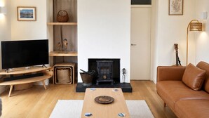 Ein modernes Wohnzimmer mit Flachbildfernseher, Kamin, Sofa und Couchtisch.