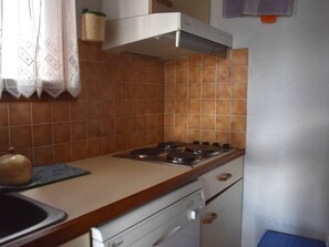 Eine Küche mit Gasherd, Geschirrspüler und einer gefliesten Spritzschutzwand.