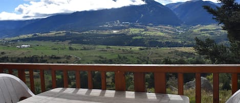 A terrace with a table and chairs overlooking a mountainous landscape.