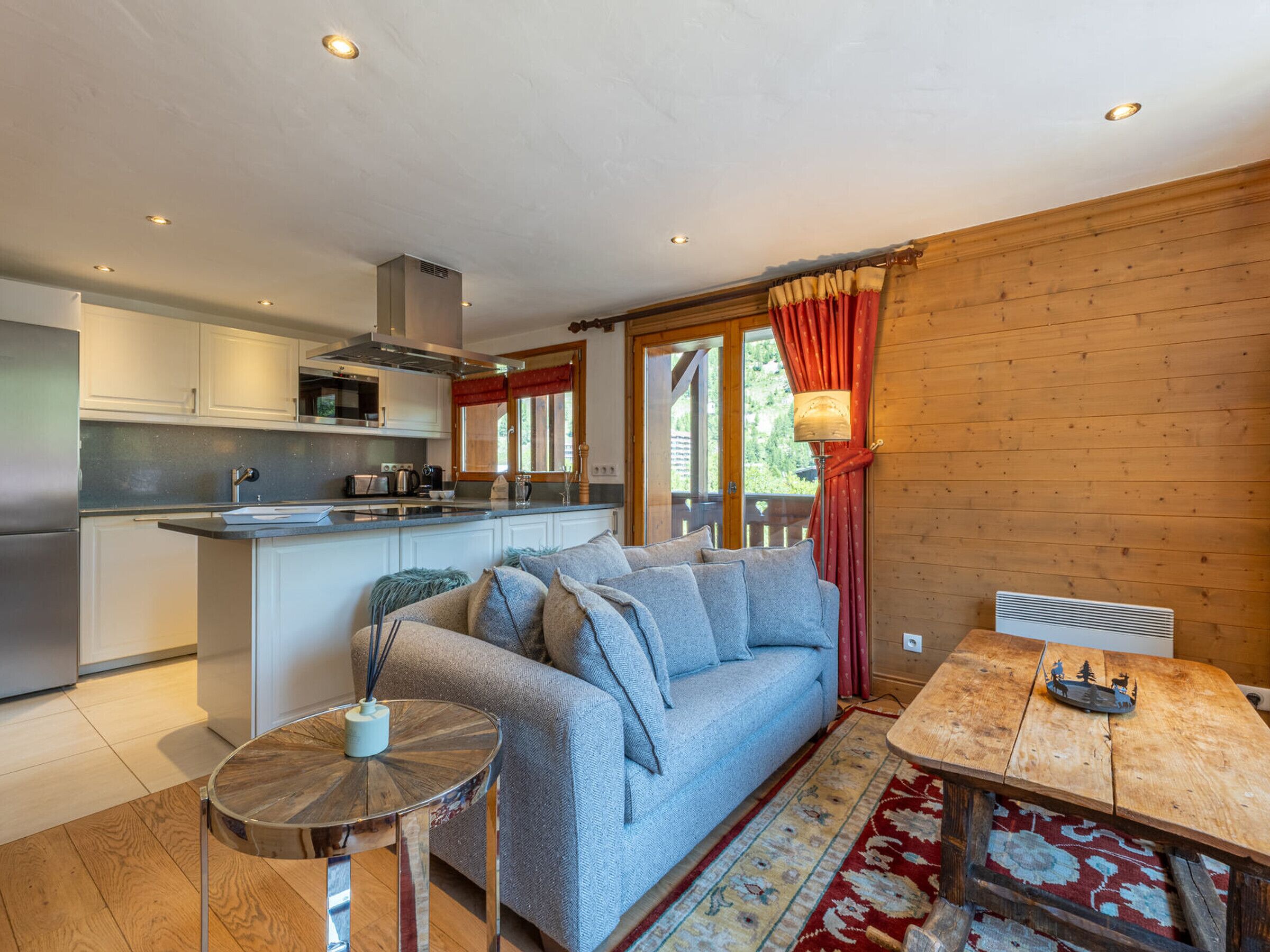 A modern kitchen with white cabinets and stainless steel appliances, a cozy living area with a sofa and a coffee table, and a dining table with a rustic design.