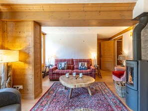 A cozy room with a fireplace, a plaid sofa, a round wooden table, and a patterned rug. - Prestige bright apartment in the center - 8 guests (Val-d'Isère)