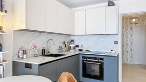 Eine moderne Küche mit Backofen, Spüle und Essbereich inklusive Tisch und Stuhl.