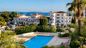 Ein Hotel mit Schwimmbad, umgeben von üppiger Vegetation und Blick auf das Meer.