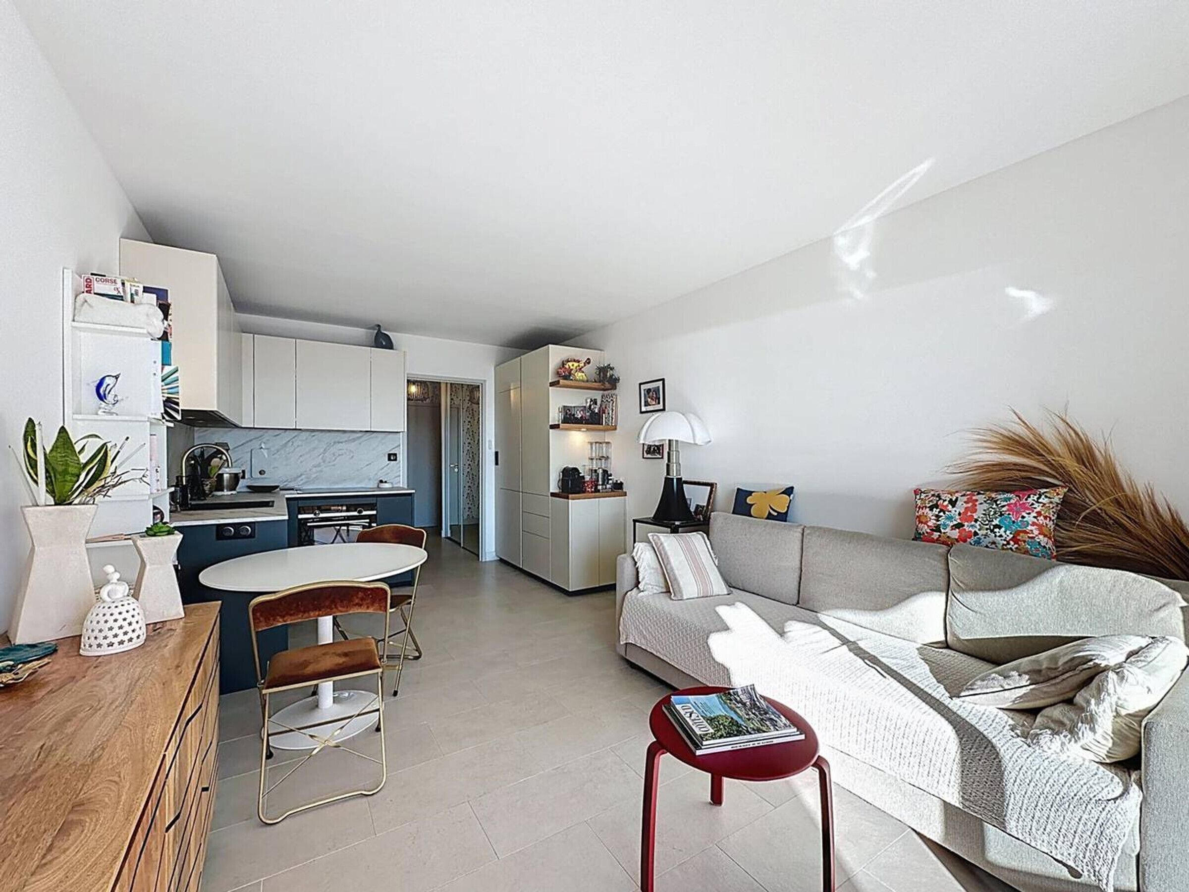 A modern living space with a kitchen, dining area, and a sofa with a side table.