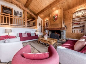 A cozy living room with a fireplace, wooden beams, and a Swiss flag. - Spacious chalet near slopes - 10 guests (Courchevel)