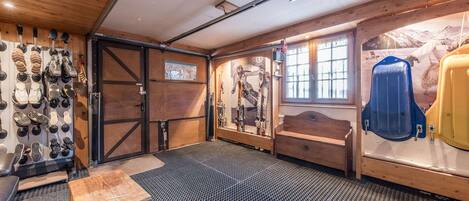 A ski lodge interior with a wooden ceiling, a ski rack, a bench, and a ski lift.
