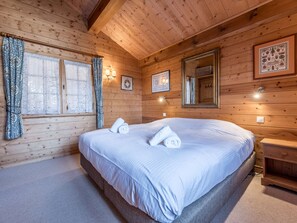A wooden cabin room with a bed, two windows with curtains, wall-mounted lights, and a mirror. - Spacious chalet near slopes - 10 guests (Courchevel)