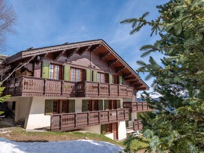 A chalet-style building with multiple balconies, wooden railings, and a mountainous backdrop. - Spacious chalet near slopes - 10 guests (Courchevel)