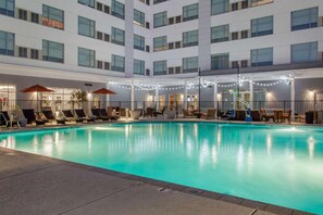 Una piscina interna con sedie a sdraio e ombrelloni, circondata da un edificio con diversi piani e finestre.