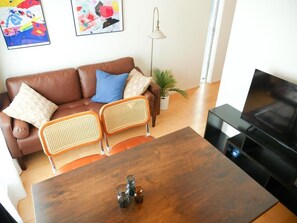 A living room with a brown leather sofa, two wicker chairs, a wooden coffee table, and a television. - MSTAY Ikebukuro One (Toshima-ku)