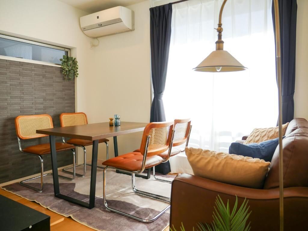 A modern living space with a dining area, a sofa, and a hanging lamp.