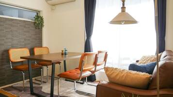 A modern living space with a dining area, a sofa, and a hanging lamp.