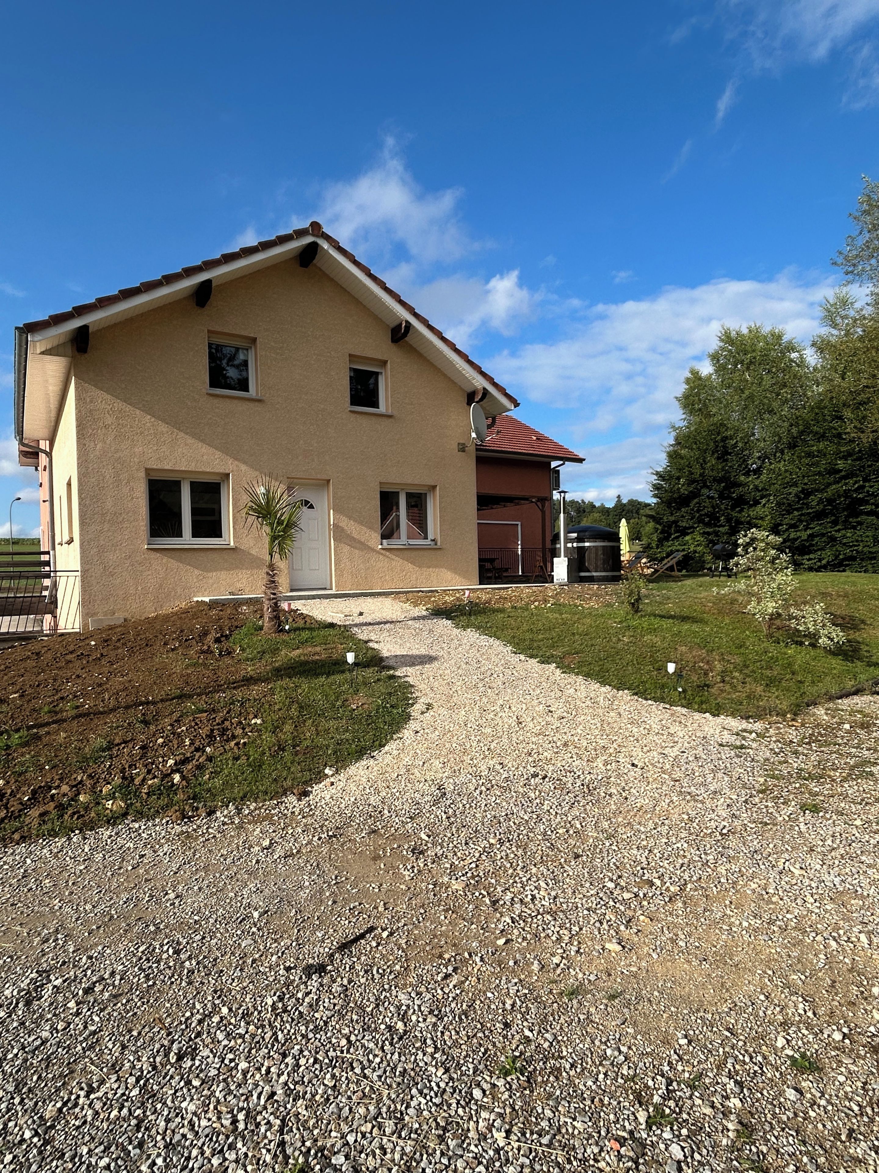 Une maison à deux étages avec une allée en gravier menant à l’entrée.