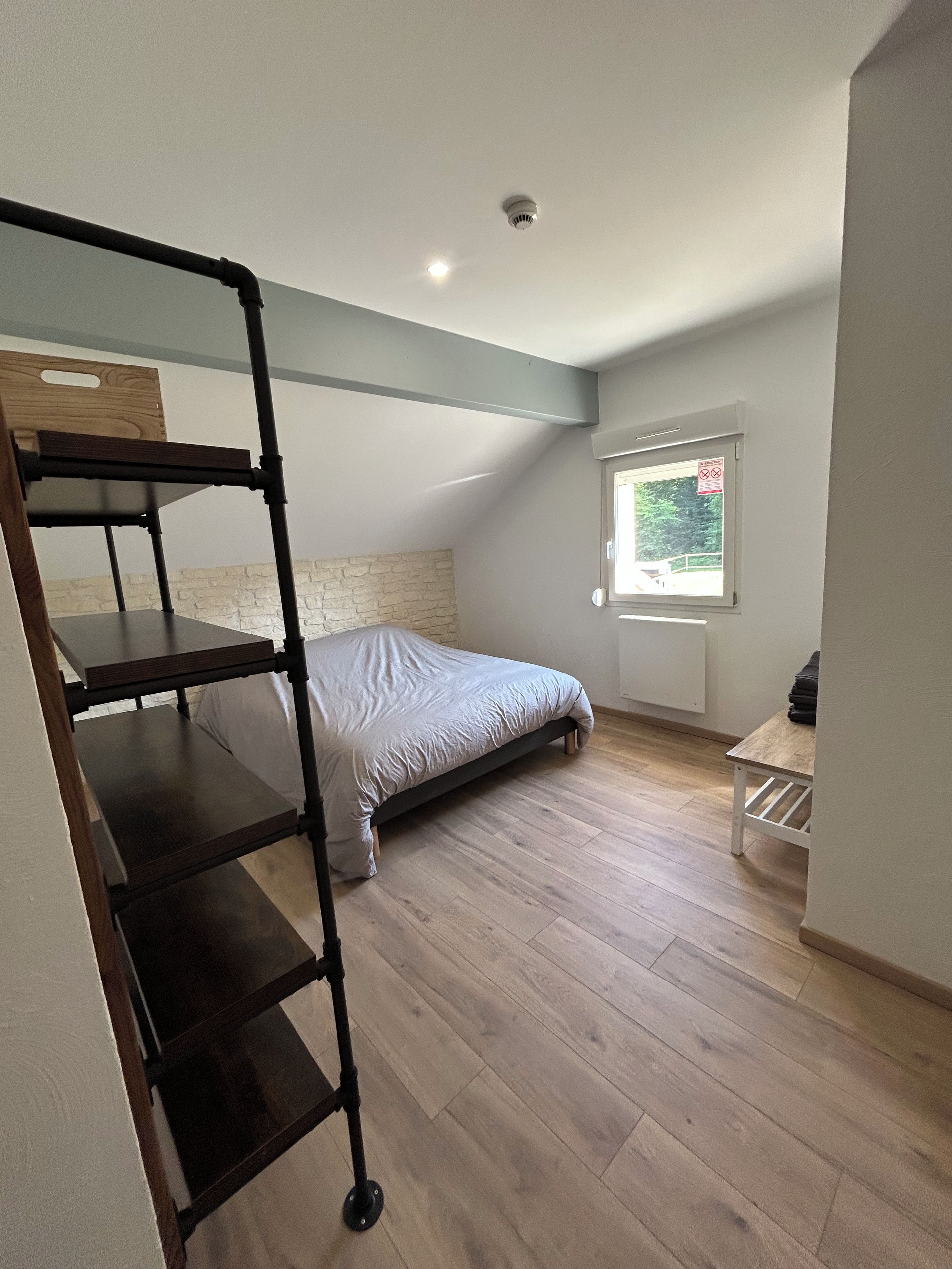 A room with a bunk bed, a desk, a chair, a window with a view, and a ceiling light.