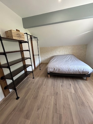 Quarto com cama, estante de madeira e parede com textura de pedra.