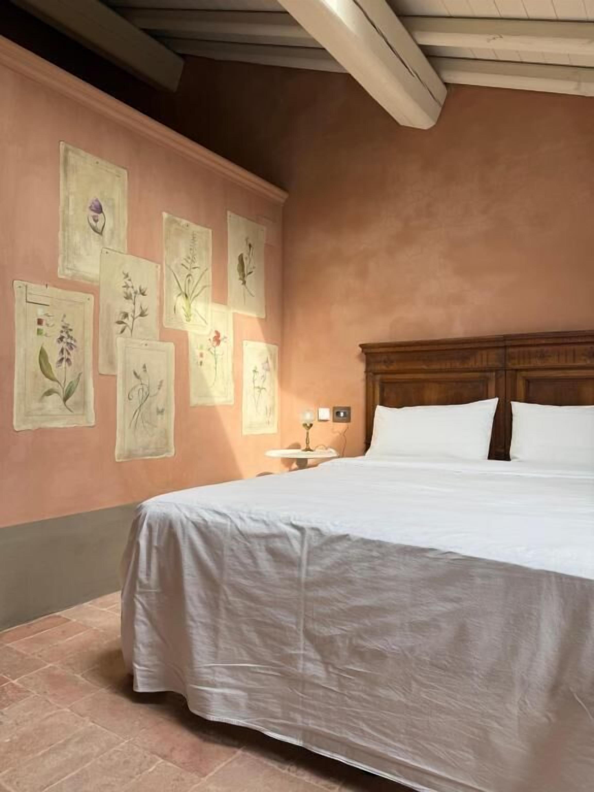 Un dormitorio con cama, mesita de noche e ilustraciones botánicas en la pared.