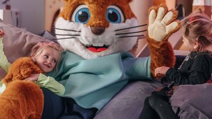 Eine Person in einem großen Hasenkostüm sitzt auf einer Couch mit zwei Kindern.