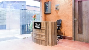 A reception desk with a sign indicating it's company-serviced, a door to the right, and a window with blinds to the left. - Super Collection O Behala (Alipur)