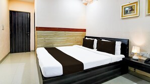 A hotel room with a bed, bedside table, lamp, and two framed pictures on the wall. - Super Collection O Behala (Alipur)