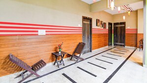 A hotel lobby with a reception desk, seating area, and a corridor leading to elevators. - Super Collection O Behala (Alipur)