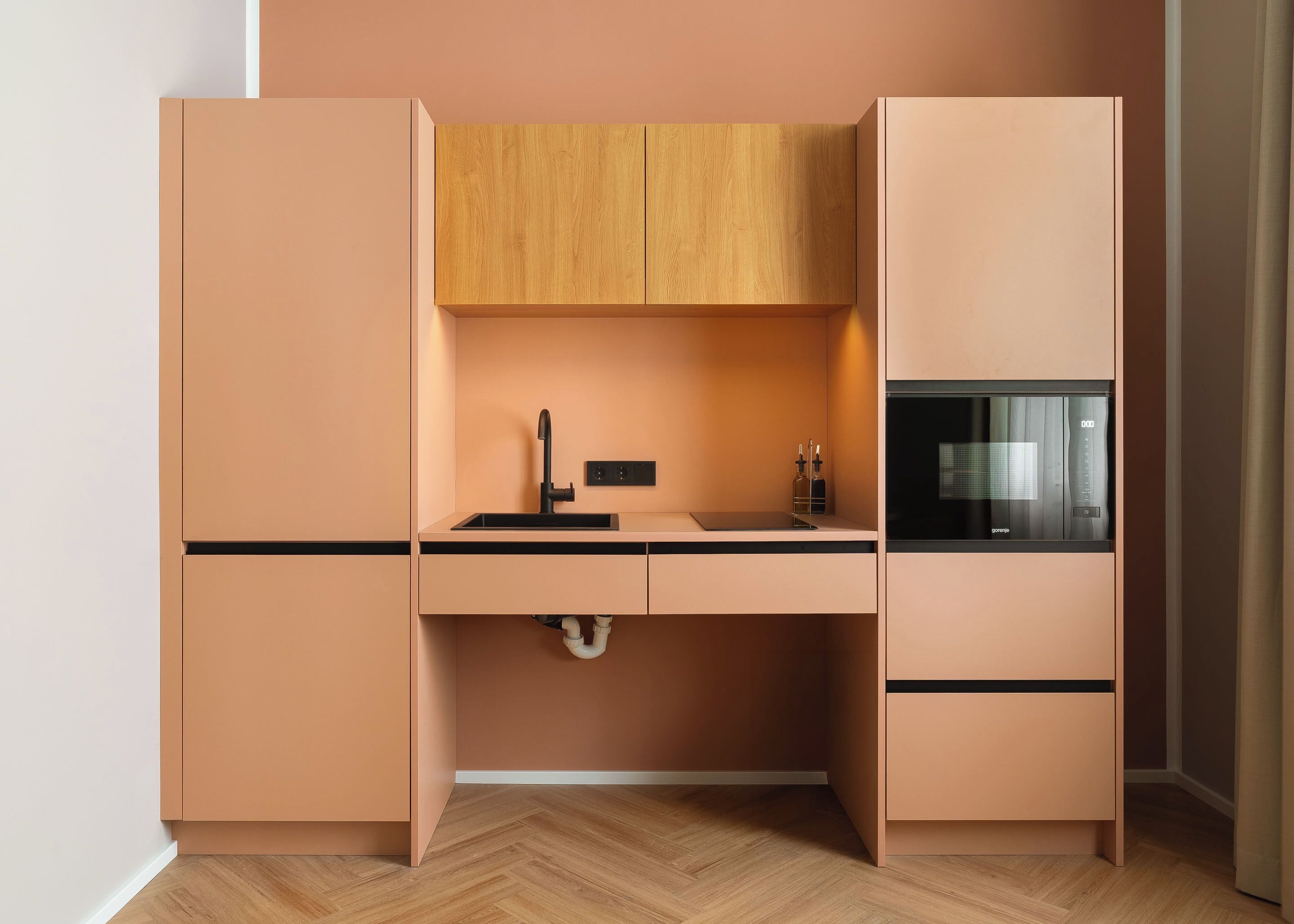 A compact kitchen with a built-in microwave, a sink with a faucet, and wooden cabinets.