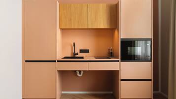 A compact kitchen with a built-in microwave, a sink with a faucet, and wooden cabinets.