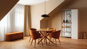 Un comedor moderno con una mesa redonda, cuatro sillas, una lámpara colgante y una estantería empotrada.