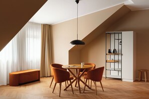 A modern dining area with a round table, four chairs, a pendant light, and a built-in shelving unit.