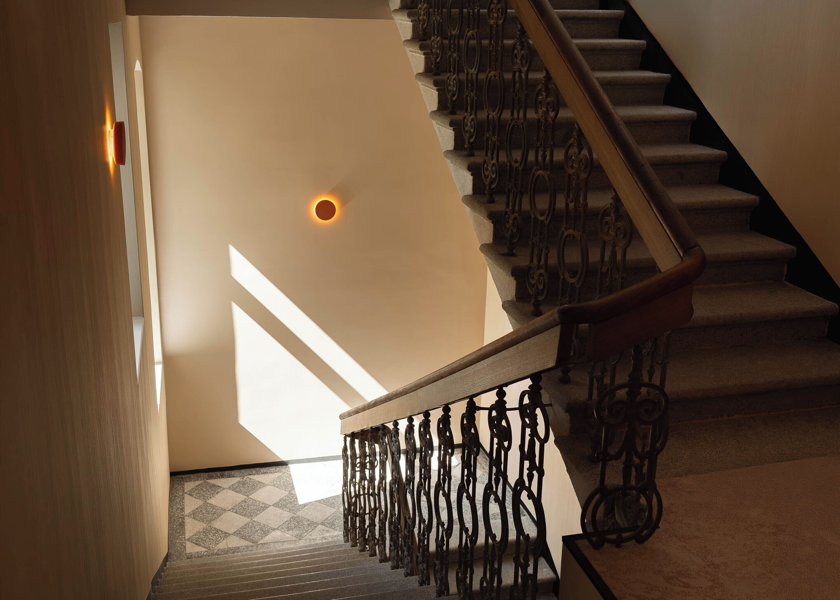 Un escalier orné de rampes en métal décoratif et doté d’un sol à motifs.