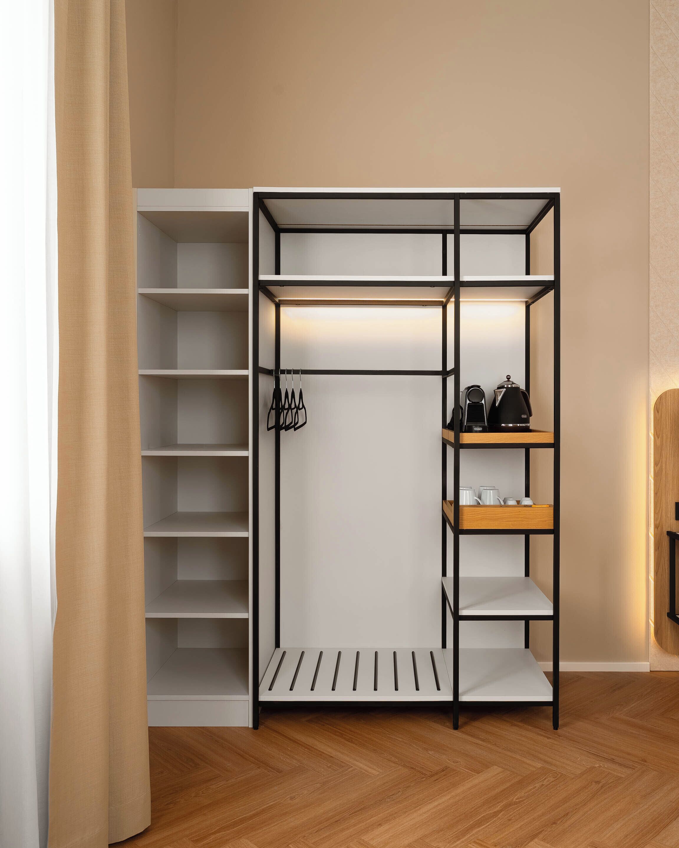 A walk-in closet with multiple shelves and hanging space, featuring a wooden floor and a beige wall.