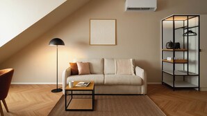 Una sala de estar moderna con un sofá, una mesa de centro, una lámpara de pie, un aire acondicionado de pared y una estantería.