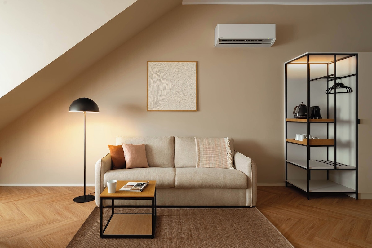 A modern living room with a sofa, a coffee table, a floor lamp, a wall-mounted air conditioner, and a shelving unit.
