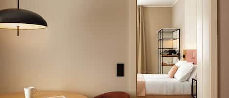 A hotel room with a bed, bedside table, and a reading area with a table and chair.