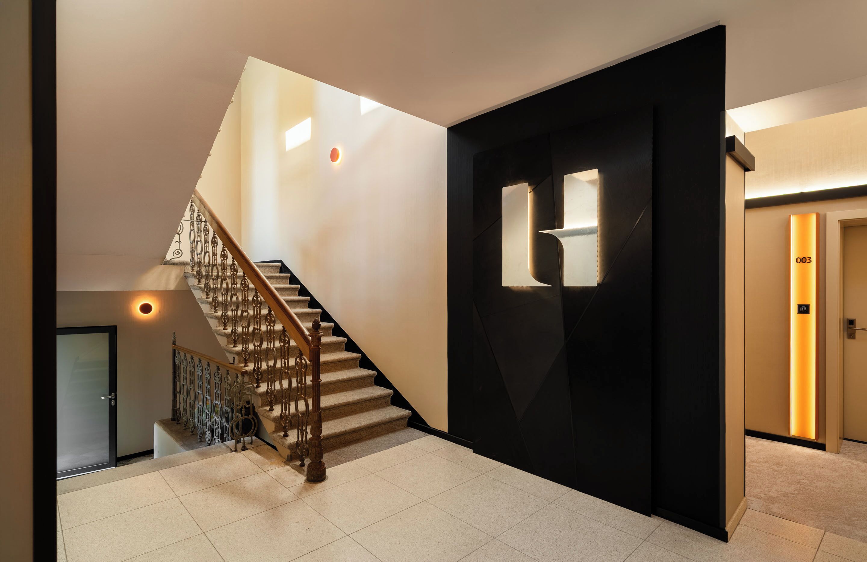 Een modern interieur met een trap, een zwarte deur met een nummer en een gang.