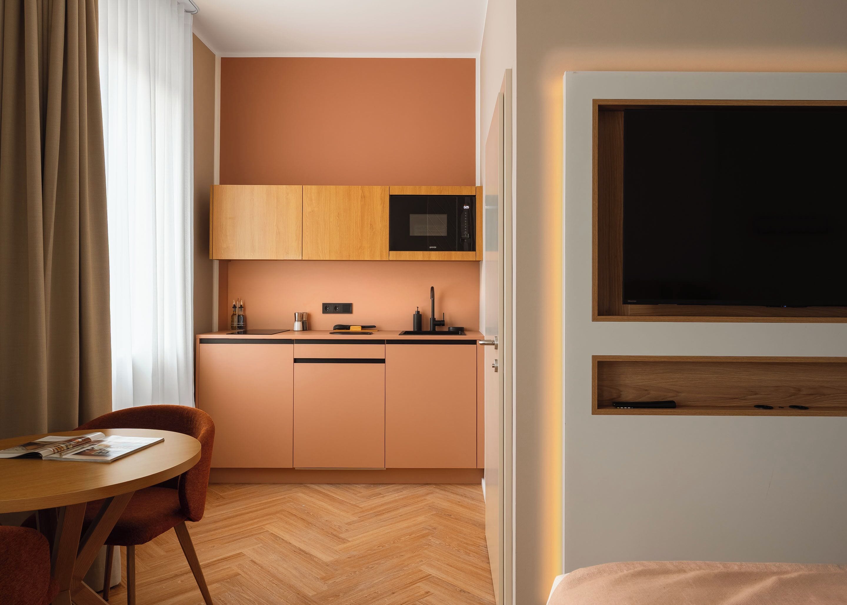 Ein kompaktes Hotelzimmer mit Küchenzeile, Essbereich und einem Bett.