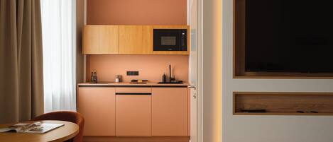 Una habitación de hotel compacta con kitchenette, comedor y cama.