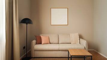 A living room with a sofa, a floor lamp, a framed picture on the wall, and a small table.