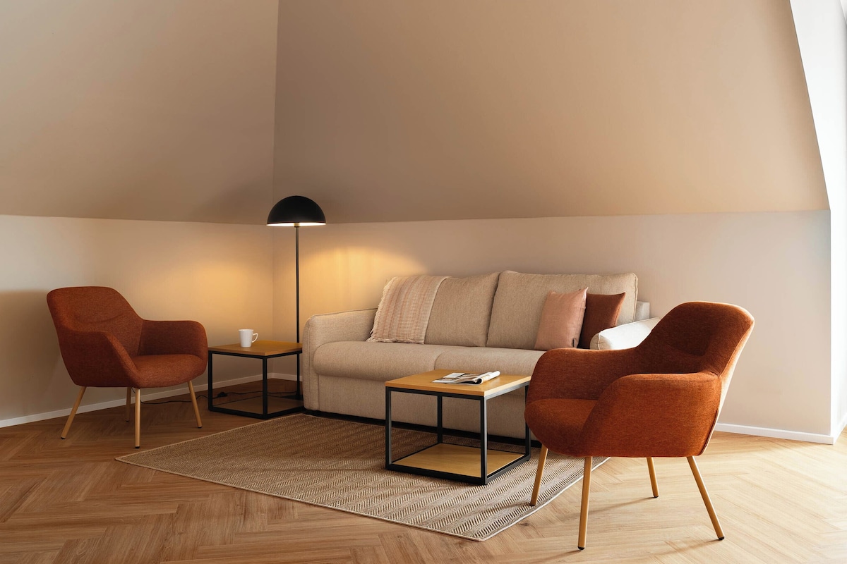 A living room with a sofa, two armchairs, a coffee table, a floor lamp, and a rug.