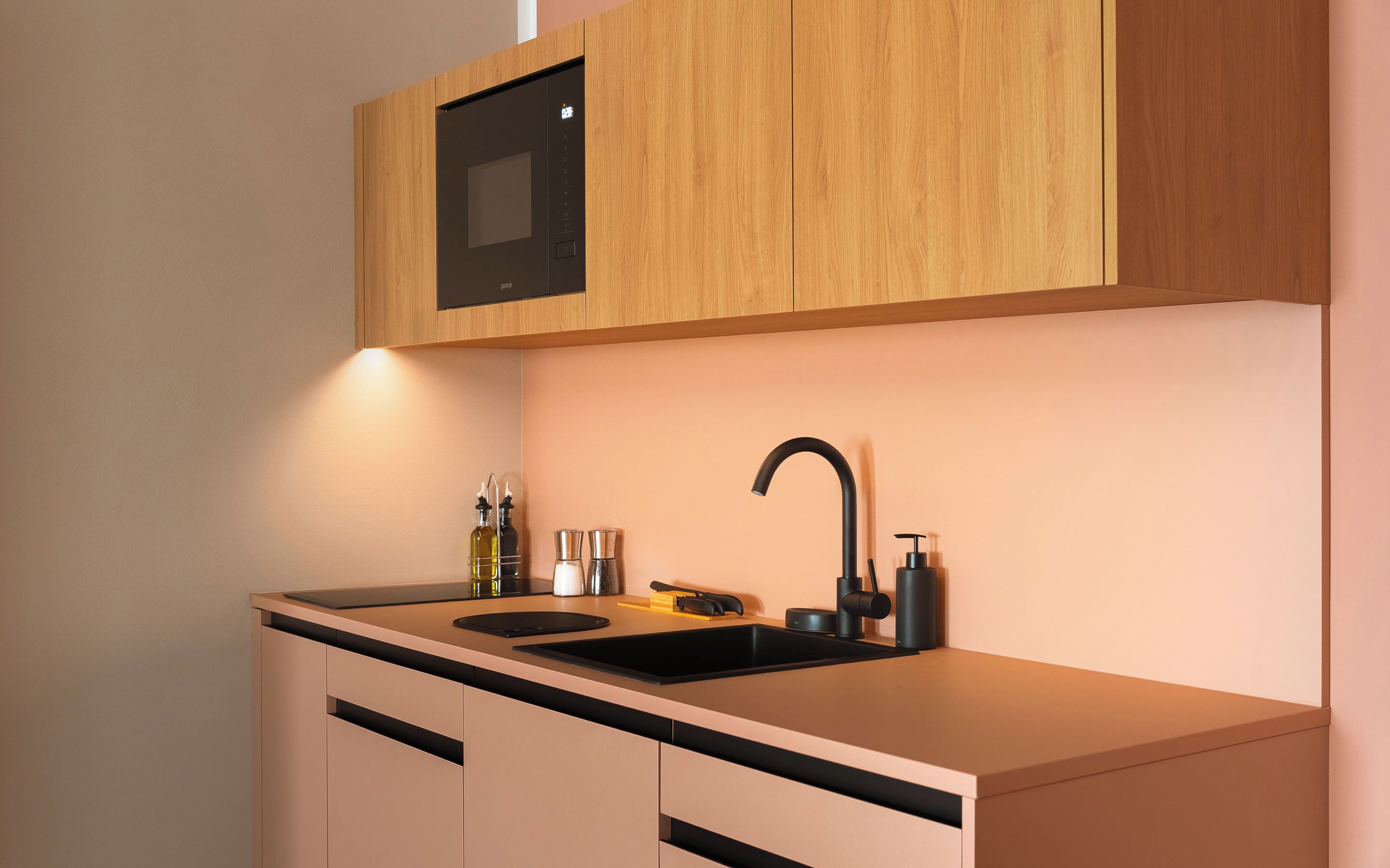 A modern kitchen with a black sink, wooden cabinets, and a built-in oven.