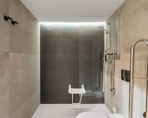 Un baño moderno con cabina de ducha de vidrio, una bañera blanca y un perchero blanco.