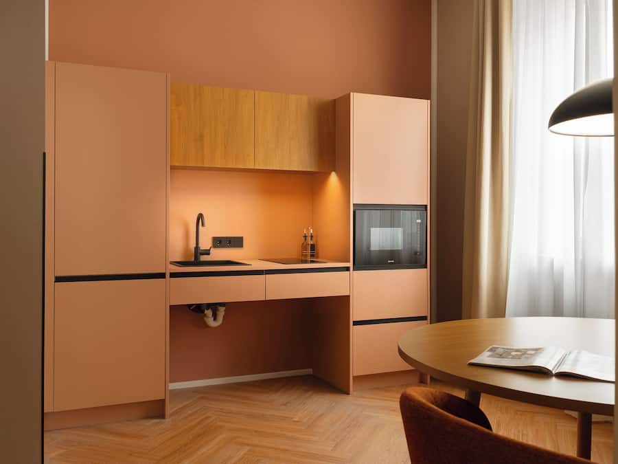 Una cocina compacta con microondas integrado, un lavamanos y armarios de madera.