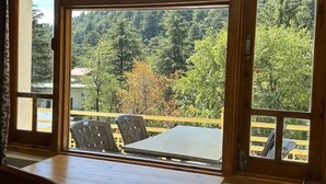 A room with a large window offering a view of a forested hillside.