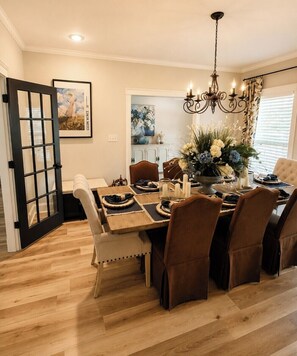 Une salle à manger avec une table en bois dressée pour six personnes, entourée de chaises rembourrées.